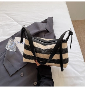 Detail of handwoven straw texture and black PU leather strap on striped shoulder bag