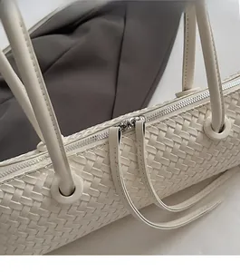 Detailed macro view of woven cream leather texture and smooth metal zipper closure