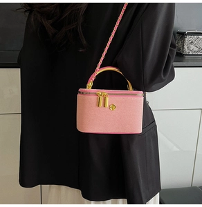 Detailed shot of pink textured mini bag with gold arch handle and metal flower emblem