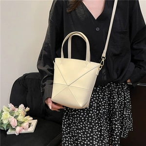 Sac seau beige chic avec coutures géométriques porté par un mannequin en décor réel