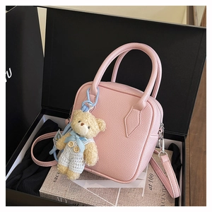 Detailed view of pink pebble leather square bag with cute bear charm in a black gift box