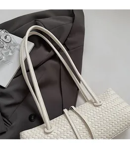 Close-up of beige woven shoulder bag with cylindrical straps and metallic zipper detail