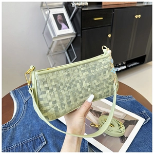Detail of light green woven leather pillow bag with floral charm and gold hardware