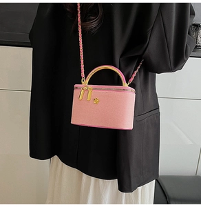 Detail of pink tweed crossbody bag with golden camellia ornament and chain strap
