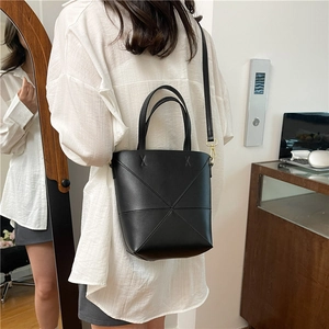 Sac seau noir minimaliste avec coutures géométriques en X et garniture dorée