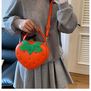 Détail du sac bandoulière en forme de fraise orange avec rivets et feuilles