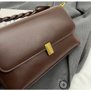 Detail of vintage dark brown crossbody bag with gold metal clasp and woven leather handle