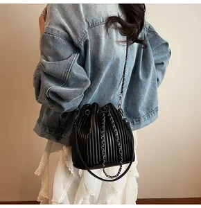 Detail of black pleated bucket bag with metallic chain strap and drawstring closure