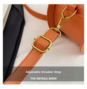 Close-up of adjustable orange leather shoulder strap with gold metal buckle and lobster clasp