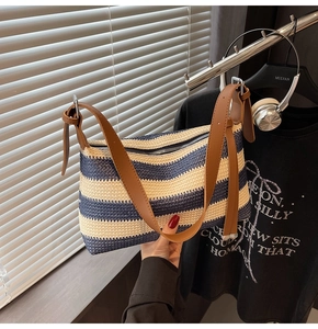 Detail of blue and white striped straw pillow bag with brown leather shoulder straps
