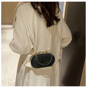 Detail of elegant black glitter evening bag with gold bow clasp and metal chain strap