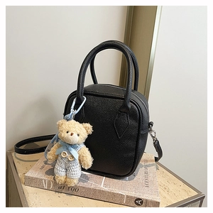 Chic black pebbled leather square bag with a cute teddy bear charm on books