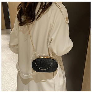 Detail of black sequined evening clutch with gold bow clasp and sleek metal chain strap