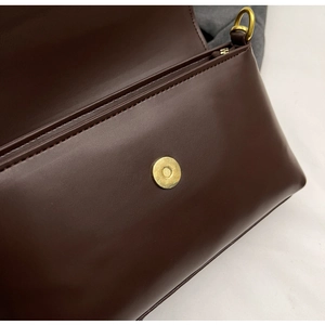Detail view of smooth brown leather bag with golden magnetic clasp and D-ring hardware