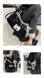 Detail of black patent leather backpack featuring number 89 patch and pearl chain accessory