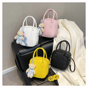 Detail of four mini square handbags in white, pink, yellow, and black with cute bear charms