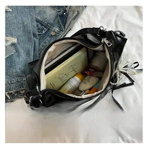Detail of black glossy tote bag interior storage with pearl bow charm and silver zipper