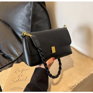 Detailed macro shot of vintage black crossbody bag with golden buckle and woven handle