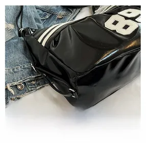 Detail of black patent leather bag featuring a white 88 patch and sporty side stripes