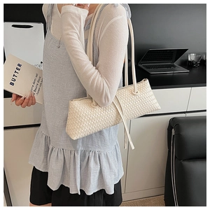 Close-up of a cream woven hobo bag showing intricate braided texture on a model's shoulder