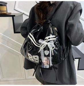 Detail of black glossy backpack featuring white stripes, number 89, and lace pearl bow