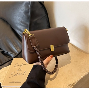 Close-up of deep brown vintage underarm bag with woven handle and gold metal clasp