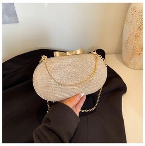Macro view of golden sequin clutch bag with metallic bow clasp and fine chain
