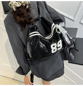 Detail of black patent leather bag with white 89 embroidery and lace pearl charms