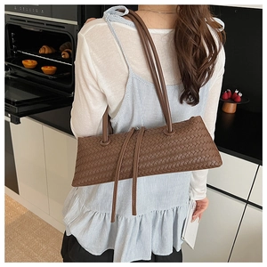 Detail of dark brown woven shoulder bag with leather texture in a kitchen setting