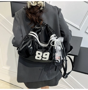 Detailed back view of a black patent leather backpack with 89 patch and lace charms