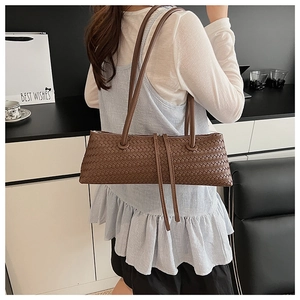 Detail of dark brown woven shoulder bag texture with long straps and tassel zip pull
