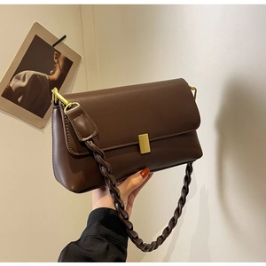 Detail of vintage brown leather handbag with gold buckle and woven shoulder strap