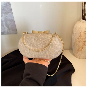 Detail of champagne gold glitter evening bag with bow clasp and fine metal chain strap