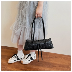 Close-up of black woven leather texture and zipper detail on an underarm baguette bag