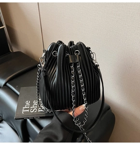 Detail of black pleated bucket bag featuring high-quality PU leather and silver chain strap