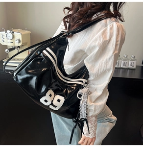 Detail shot of a black glossy shoulder bag with number 89 patch and white racing stripes