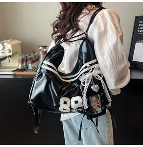 Detail of glossy black patent leather tote with white stripes, 88 patch and pearl charms