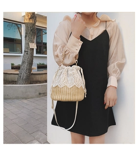 Detail of the woven straw bucket bag with delicate white lace crochet and gold chain