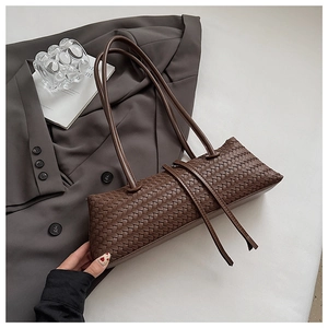 Macro detail of dark brown woven leather baguette bag with handmade texture and straps
