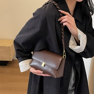 Vintage dark brown leather shoulder bag with gold clasp and woven strap on model