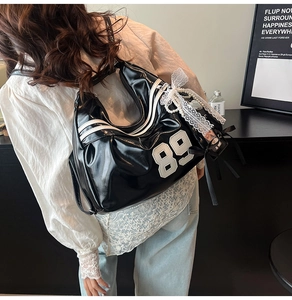 Detail of glossy black backpack with white number embroidery and pearl lace charm
