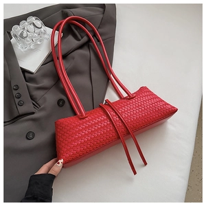 Detail shot of a red woven leather baguette bag with dual slim shoulder straps
