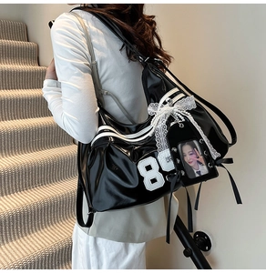 Detail of glossy black patent leather bag with white lace bow and pearl charm accents