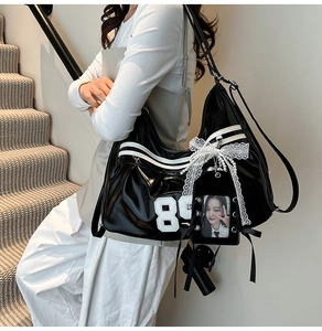Detail of black glossy hobo bag with number 85 print and white lace bow accessory