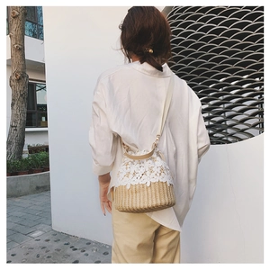Detail of hand-woven straw bucket bag featuring elegant white lace floral embroidery