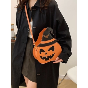 Halloween pumpkin shoulder bag with a black wizard hat and metal bat accessory on a model