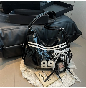 Detail of black faux leather tote with number 89 print, lace bow and heart charm
