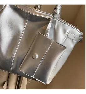 Dettaglio della borsa tote argento con una piccola pochette rimovibile e fibbia in metallo