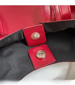 Detailed close-up of the magnetic buckle closure on a premium red leather handbag