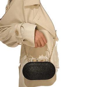 Elegant black oval evening bag with glitter finish, gold handle and chain shoulder strap